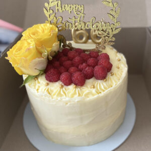 vanilla frosted cake topped with raspberries